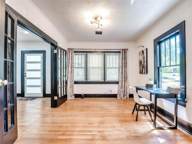 office space featuring crown molding, french doors, light hardwood / wood-style floors, and a textured ceiling