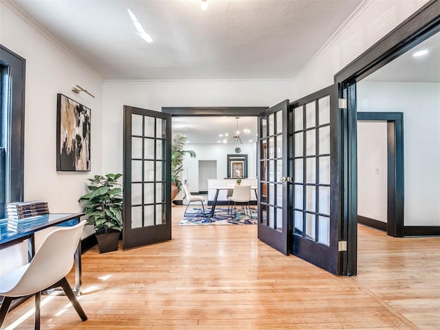 office space featuring french doors, an inviting chandelier, light hardwood / wood-style floors, a textured ceiling, and ornamental molding