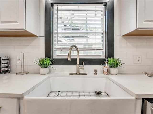 interior details with backsplash, white cabinetry, and sink