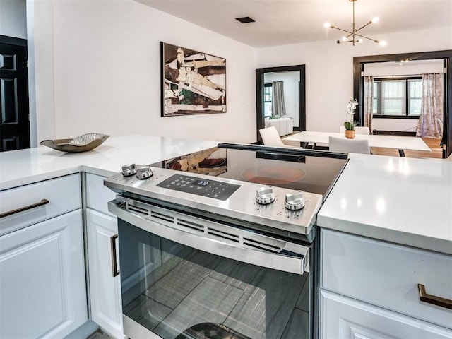 kitchen featuring electric stove, white cabinetry, and a chandelier