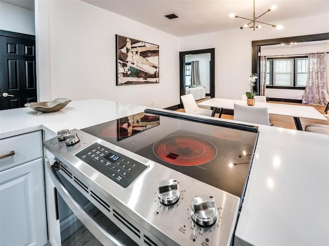 kitchen featuring white cabinets, an inviting chandelier, and stainless steel range with electric cooktop