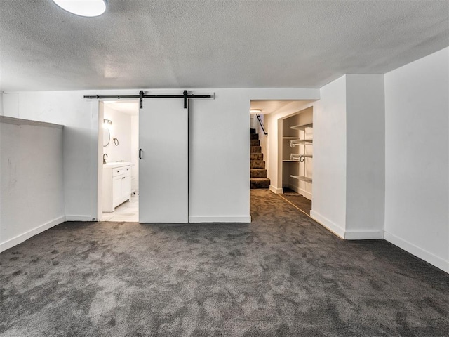 carpeted spare room with a textured ceiling and a barn door