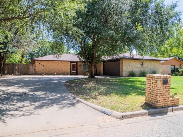 ranch-style home featuring a garage and a front lawn