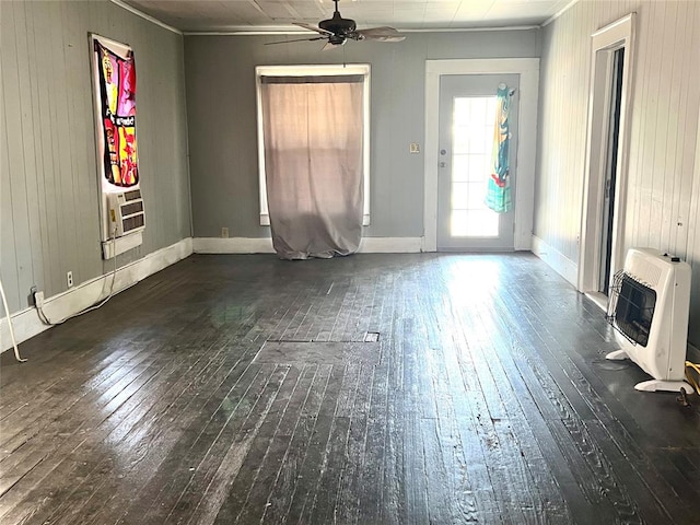 unfurnished room with ceiling fan, wood walls, dark hardwood / wood-style flooring, and heating unit