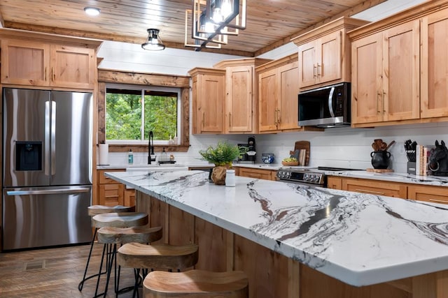 kitchen with sink, hanging light fixtures, stainless steel appliances, a kitchen breakfast bar, and wood ceiling