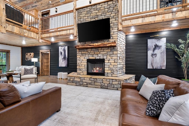 living room featuring a fireplace, wooden walls, and a high ceiling