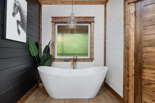 bathroom featuring hardwood / wood-style flooring, a washtub, and wooden walls