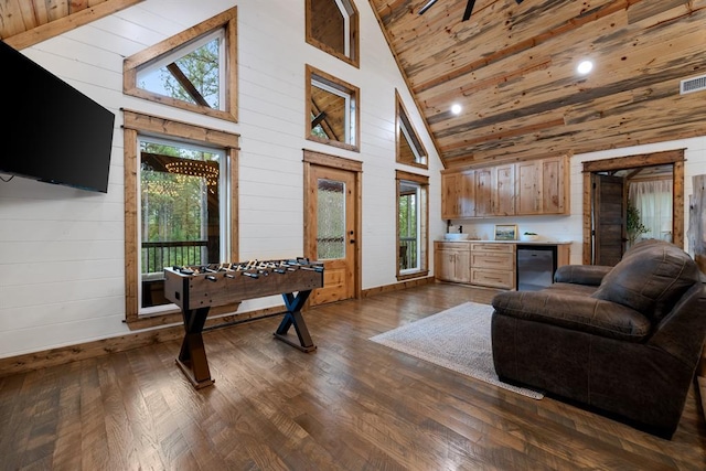 living room with wooden walls, high vaulted ceiling, plenty of natural light, and dark wood-type flooring