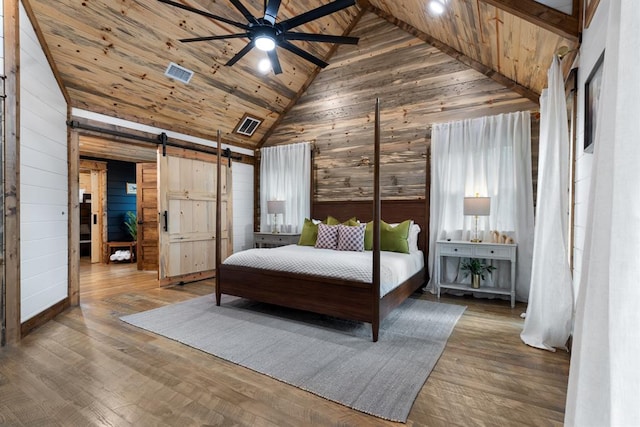 bedroom with hardwood / wood-style floors, a barn door, ceiling fan, and wooden ceiling