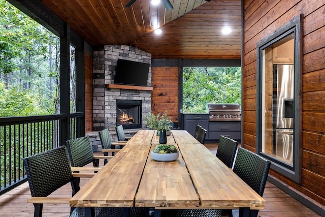 interior space featuring an outdoor stone fireplace, ceiling fan, and a grill