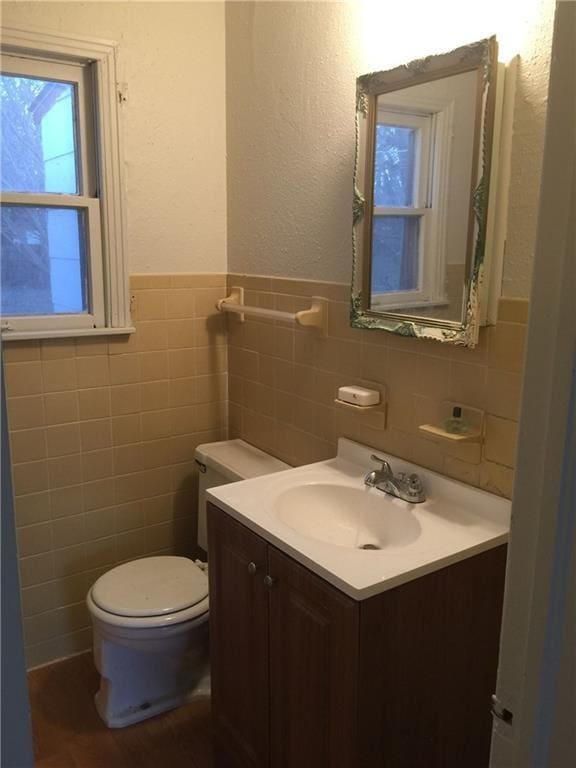 bathroom featuring vanity, toilet, and tile walls