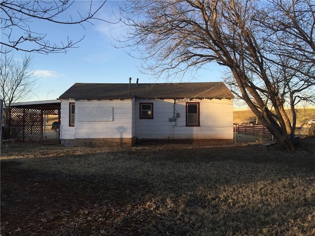 back house at dusk with a carport and a lawn