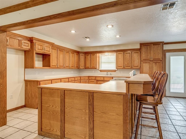 8015 County St Unit 2610, Hinton, OK 73047 - kitchen featuring light countertops, a breakfast bar area, a kitchen island, light tile patterned flooring, and a textured ceiling