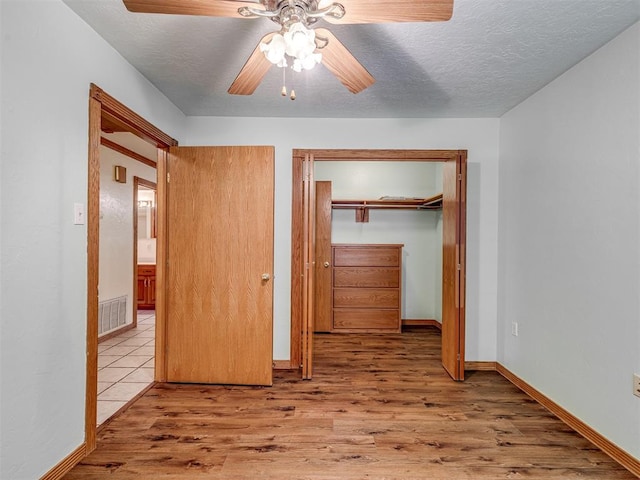 8015 County St Unit 2610, Hinton, OK 73047 - unfurnished bedroom featuring wood finished floors, a textured ceiling, a ceiling fan, and a closet