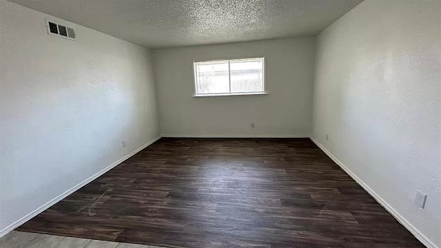 spare room with dark hardwood / wood-style floors and a textured ceiling