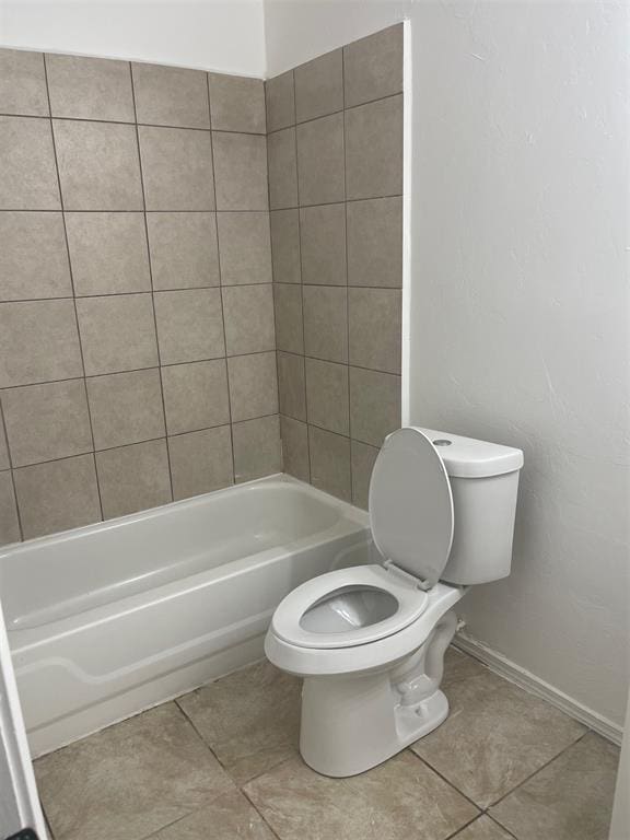 bathroom featuring tile patterned floors, tiled shower / bath, and toilet