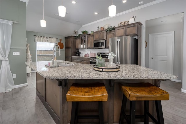 kitchen with a large island, sink, hanging light fixtures, stainless steel appliances, and a breakfast bar area