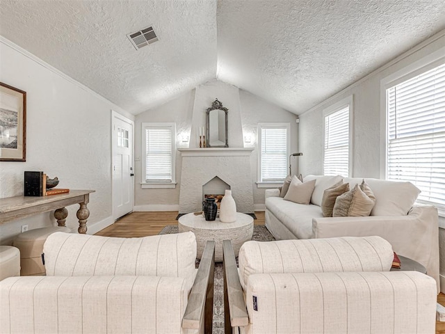 living room featuring a textured ceiling, light hardwood / wood-style floors, and lofted ceiling