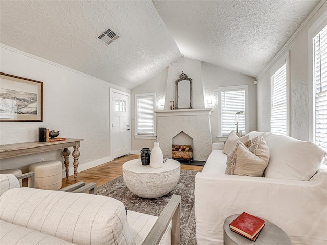 living room with a textured ceiling, light hardwood / wood-style flooring, and vaulted ceiling