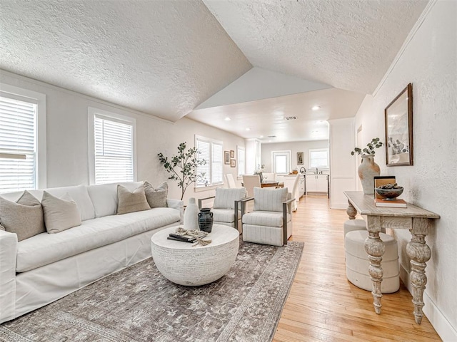 living room with light wood-type flooring, lofted ceiling, and a textured ceiling