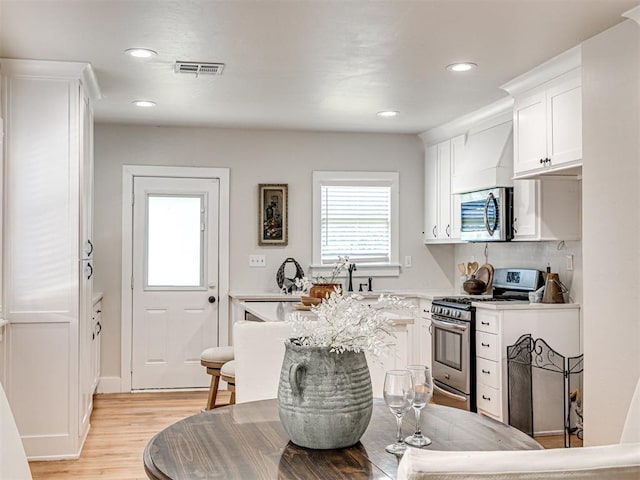 kitchen featuring white cabinetry, light wood-type flooring, and appliances with stainless steel finishes