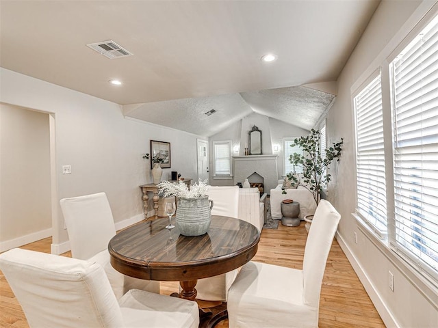 dining area with vaulted ceiling, light hardwood / wood-style flooring, and a healthy amount of sunlight