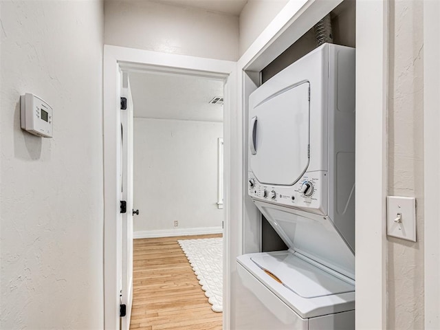 laundry area featuring hardwood / wood-style flooring and stacked washer / drying machine