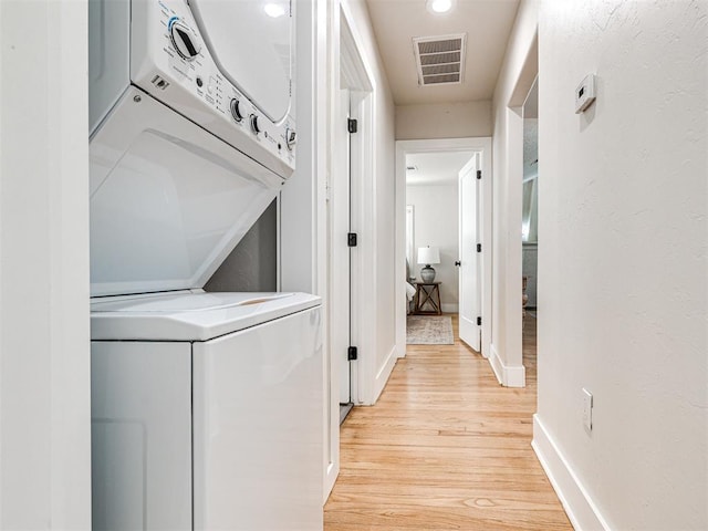 washroom with light hardwood / wood-style flooring and stacked washer and clothes dryer