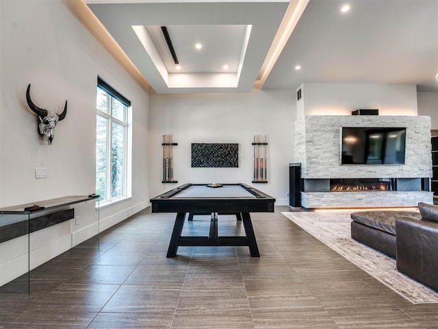 recreation room featuring a stone fireplace, billiards, and a tray ceiling