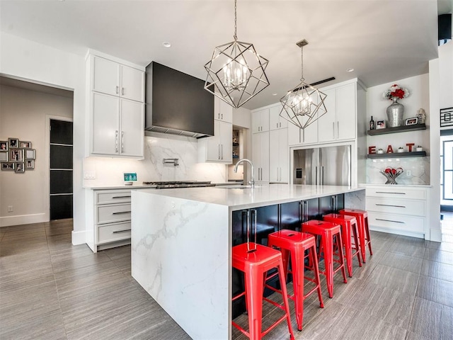 kitchen featuring white cabinets, a spacious island, stainless steel built in refrigerator, and a breakfast bar area