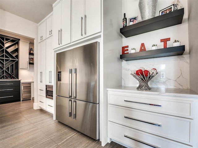 kitchen featuring white cabinets, appliances with stainless steel finishes, tasteful backsplash, and beverage cooler