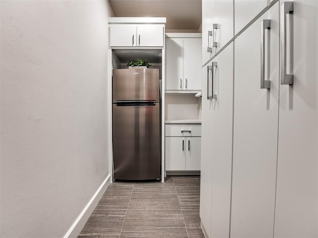 kitchen with stainless steel fridge, white cabinetry, white refrigerator, and light tile patterned floors