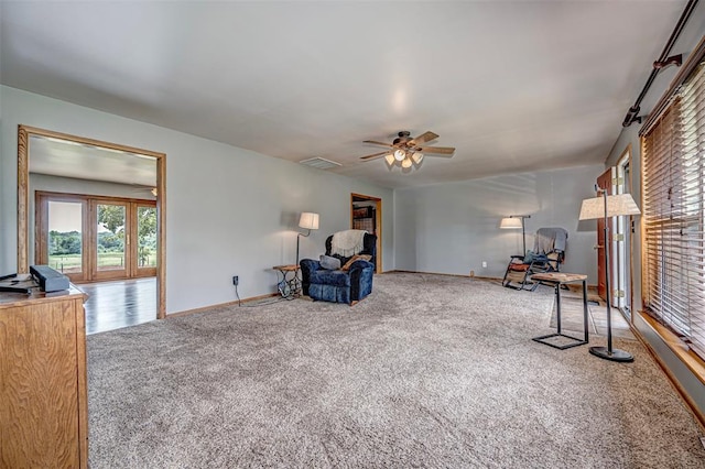 living area featuring carpet and ceiling fan