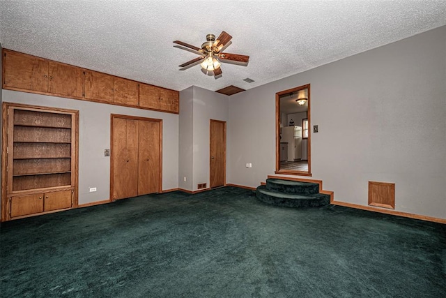 unfurnished living room featuring ceiling fan, dark carpet, and a textured ceiling