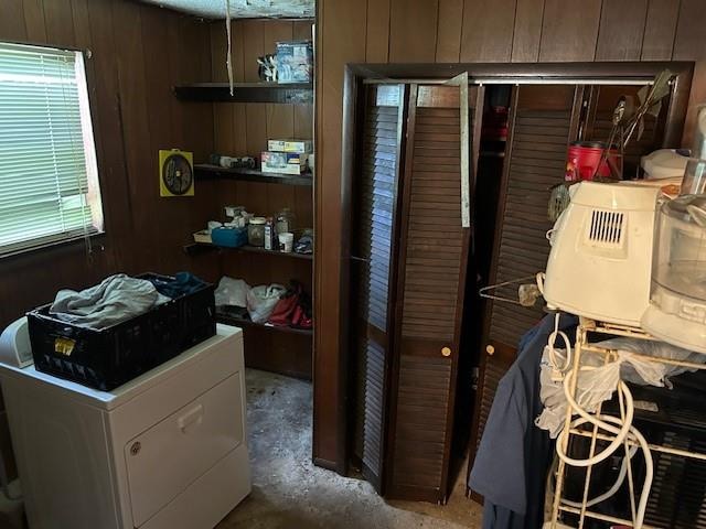 interior space featuring washer / clothes dryer, wood walls, and concrete floors