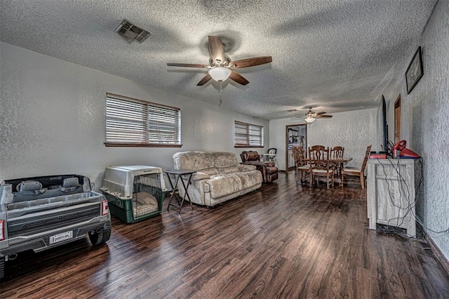 living room featuring a textured ceiling, dark hardwood / wood-style floors, and ceiling fan