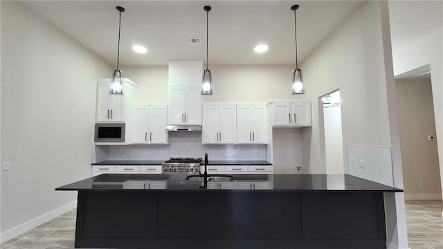 kitchen featuring white cabinetry, sink, hanging light fixtures, stainless steel appliances, and decorative backsplash