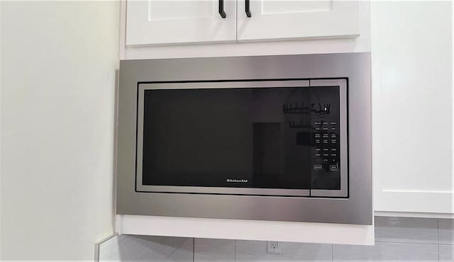 details featuring white cabinets and stainless steel microwave