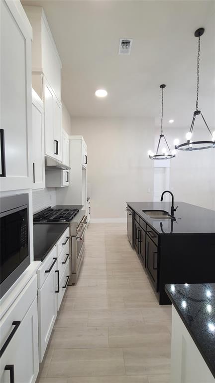 kitchen with white cabinets, appliances with stainless steel finishes, an inviting chandelier, and sink