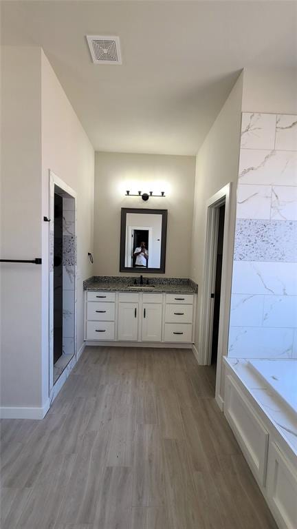 bathroom with hardwood / wood-style floors, vanity, and separate shower and tub