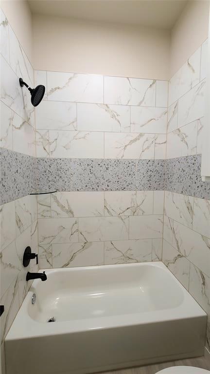 bathroom featuring toilet and tiled shower / bath