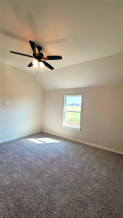 empty room featuring carpet floors, ceiling fan, and lofted ceiling