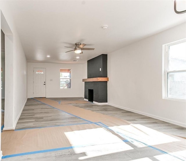 unfurnished living room with a fireplace, hardwood / wood-style flooring, and ceiling fan