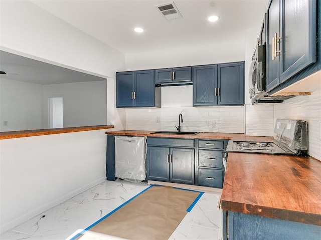 kitchen featuring dishwasher, sink, decorative backsplash, blue cabinetry, and butcher block counters