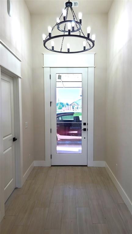 doorway to outside featuring wood-type flooring and a chandelier