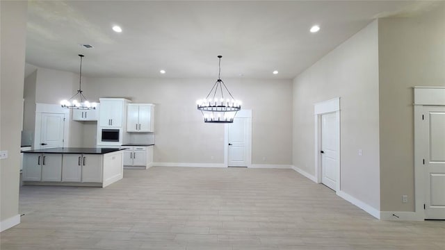 kitchen with white cabinets, light hardwood / wood-style floors, an inviting chandelier, and hanging light fixtures