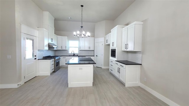 kitchen with white cabinetry, stainless steel stove, hanging light fixtures, and a kitchen island