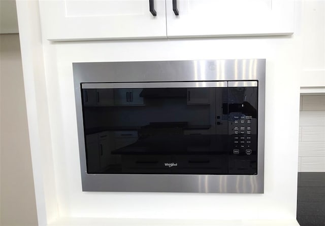 interior details with white cabinets and stainless steel microwave