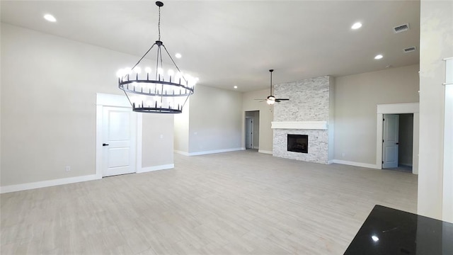 unfurnished living room featuring a fireplace, ceiling fan with notable chandelier, and light wood-type flooring