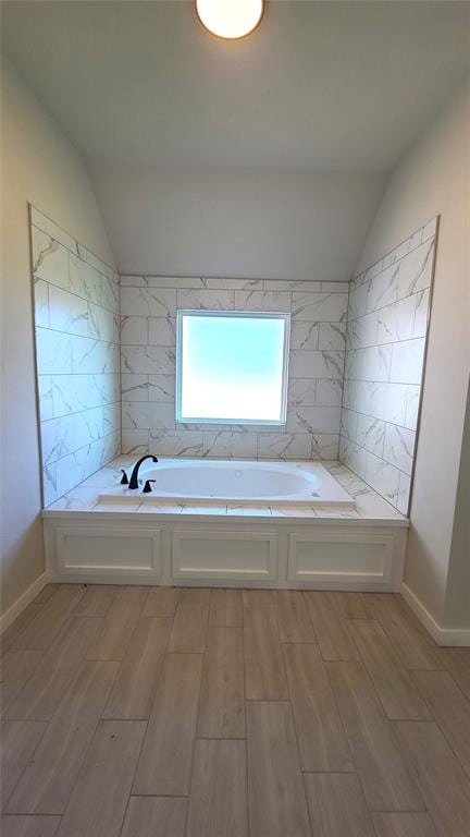 bathroom featuring tile walls, a bathtub, lofted ceiling, and hardwood / wood-style flooring